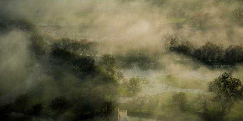 一位女性坐在书架前,旁边是一部智能设备,设备屏幕上显示一本虚拟书籍的封面。说明:AI推荐书籍的场景。